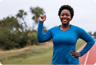 Smiling woman in a blue top flexing her arm outdoors