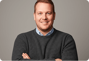 Man in a grey sweater with his arms crossed